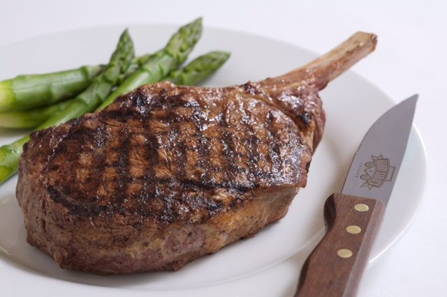 Steak and asparagus on plate next to knife at Hotel Chicago Downtown, Autograph Collection