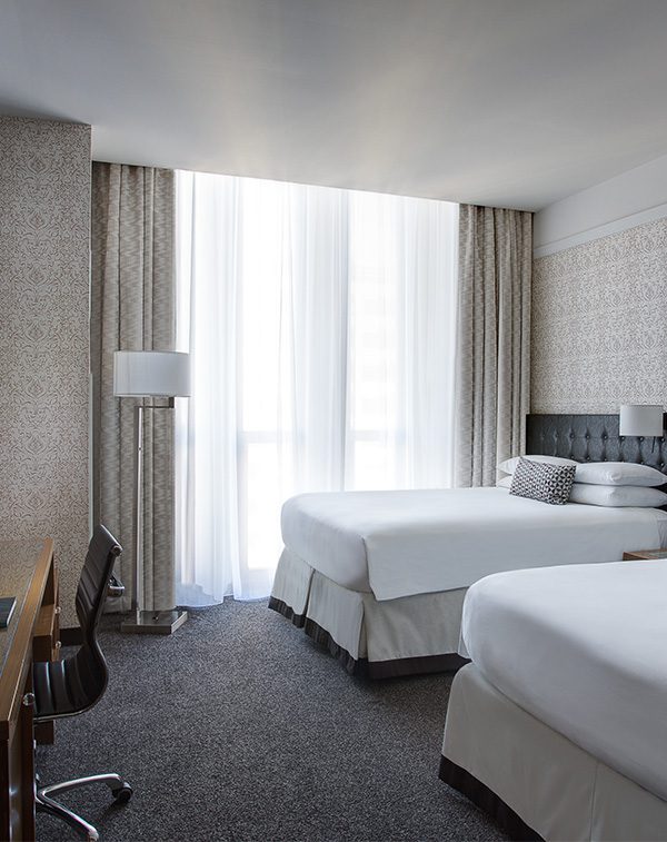 Two beds with white linens in front of white curtains and pillows at Hotel Chicago Downtown, Autograph Collection