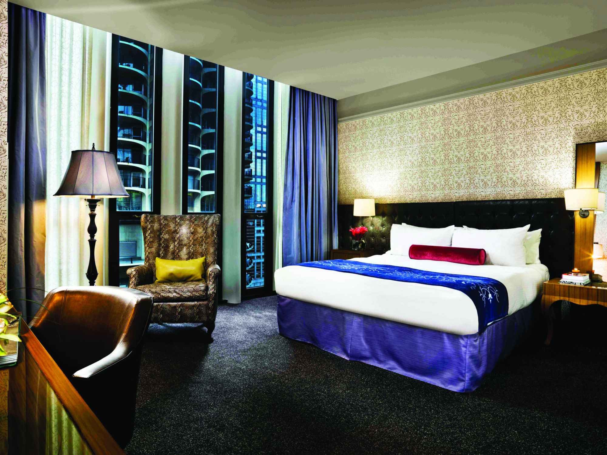 Bed with blue and white linens near brown chairs overlooking buildings at Hotel Chicago Downtown, Autograph Collection