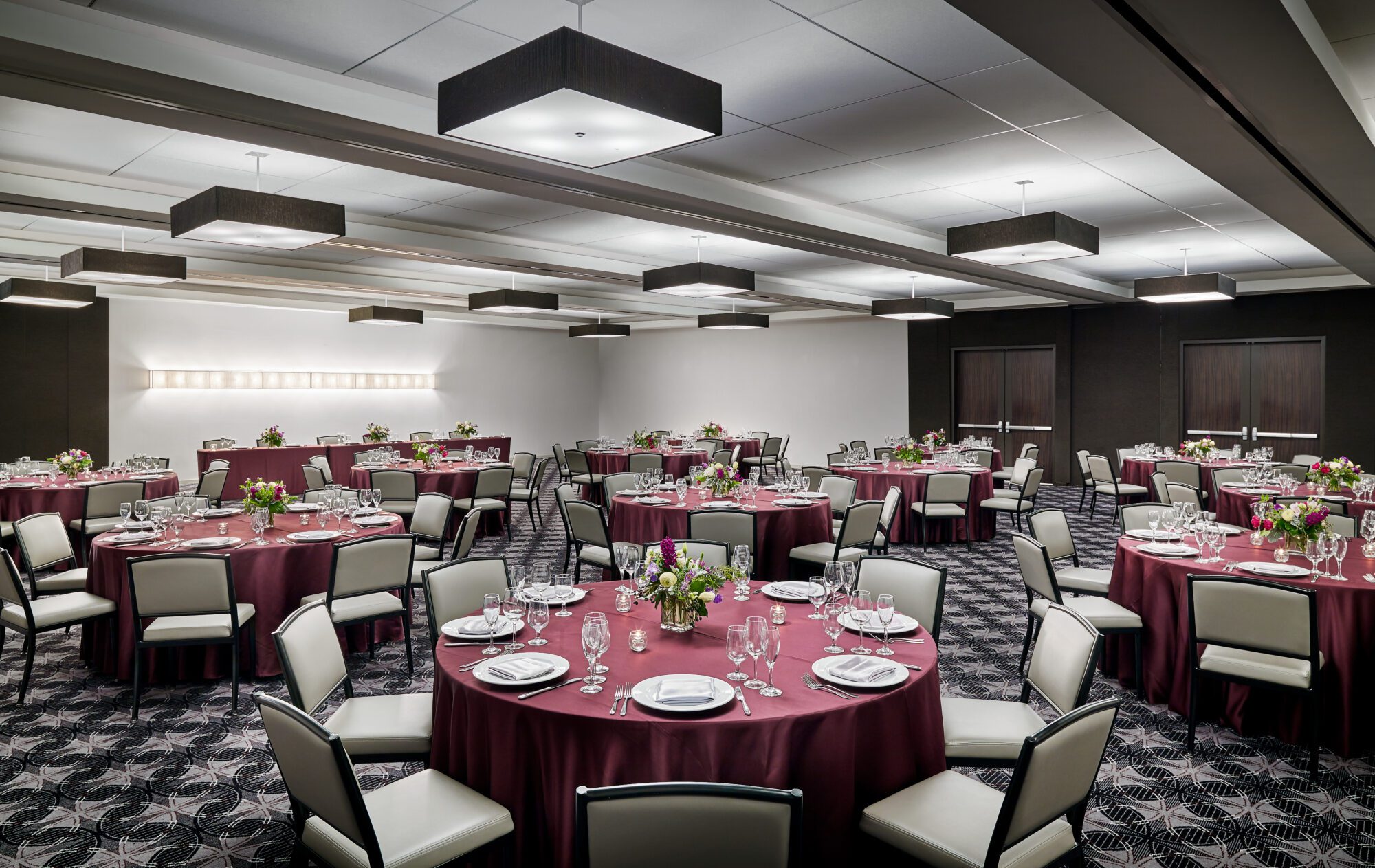 Ballroom at a downtown Chicago hotel set with round tables and maroon linens, dinner setting and florals on the tables