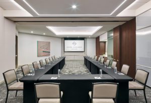 Meeting room in downtown Chicago, set in a u shaped setting with black linened tables, water bottles and pen and paper