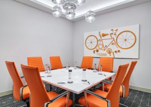 White meeting room with orange chairs and white table at Hotel Chicago Downtown, Autograph Collection