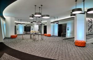 Lunch buffet setup on the lobby area of the meeting rooms with white walls, black modern doors, orange seating benches and silver rolling buffet tables at Hotel Chicago Downtown, Autograph Collection