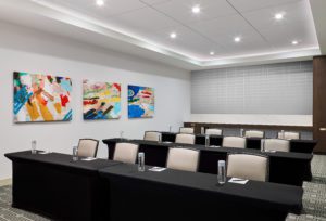 Boardroom with white chairs in front of tables with black linens with glasses of water and water bottles at Hotel Chicago Downtown, Autograph Collection