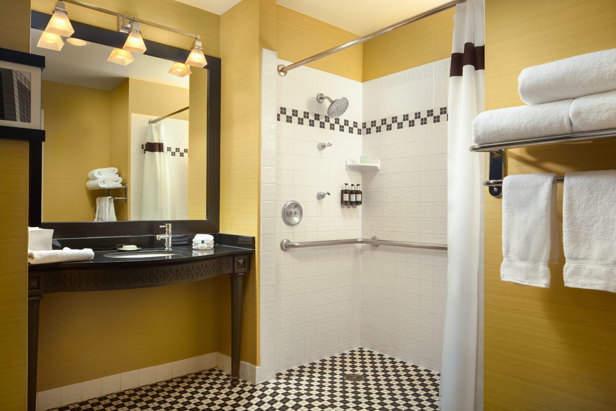 ADA roll in shower with black and white tile and orange walls next to towels at Hotel Chicago Downtown, Autograph Collection