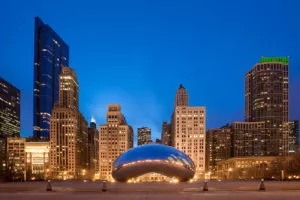 Luxury photo of Cloud Gate ("The Bean") in Chicago’s Millennium Park, with city skyscrapers glowing at dusk—perfect for any gallery.