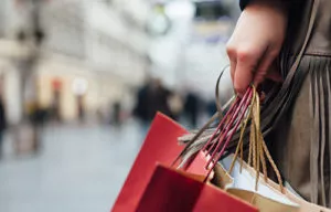 Close-up of a person’s hand holding shopping bags with a blurred city street near a hotel in Chicago and the Magnificent Mile in the background.